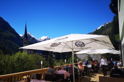 a group of people sitting at a table under an umbrella at Hotel Rupertihaus in Heiligenblut