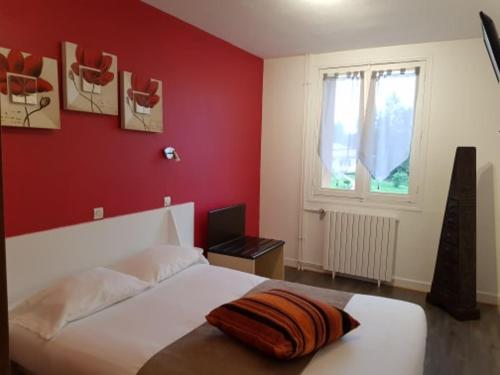 a bedroom with a white bed with a red wall at le relais des forêts in Blessac