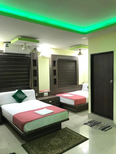 1 dormitorio con 2 camas y techo verde en Highland Inn Hotel en Mangalore