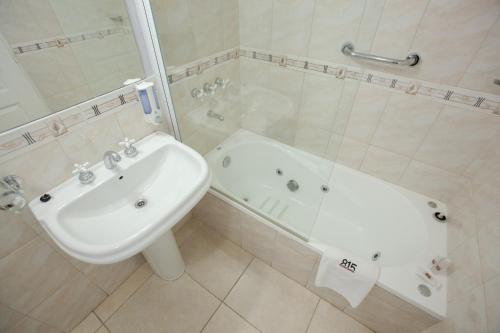 a bathroom with a sink and a tub and a toilet and a bath tub at Apart Hotel Rivadavia 815 in Neuquén