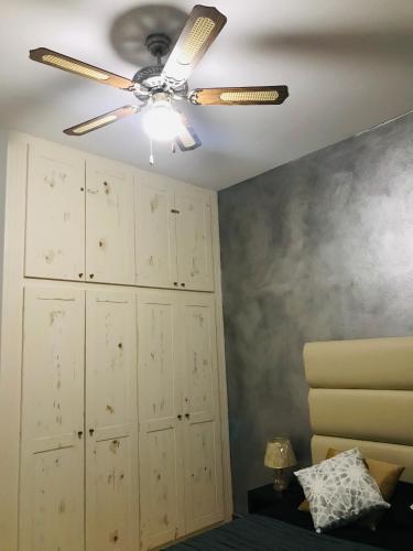 a ceiling fan in a room with a bed at Blue Eagle Guesthouse - Casa de hospedes in Santa Maria