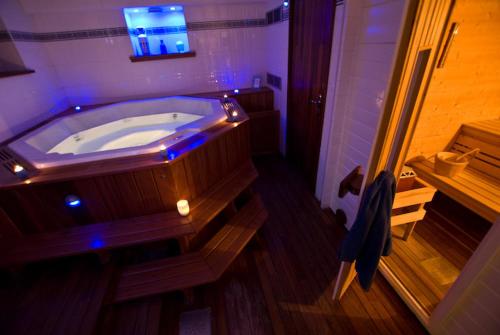 a large wooden tub in a bathroom with purple lights at Hôtel L'Yeuse - Les Collectionneurs in Châteaubernard