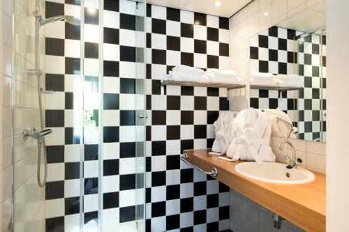 a bathroom with a black and white checkered wall at Hotel Parkzicht Eindhoven in Eindhoven