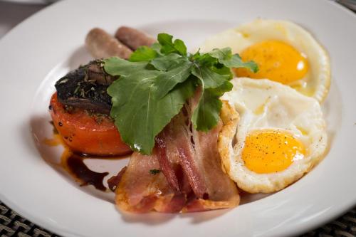 a plate of breakfast food with eggs bacon and sausage at Riboville Boutique Hotel And Restaurant in Midrand