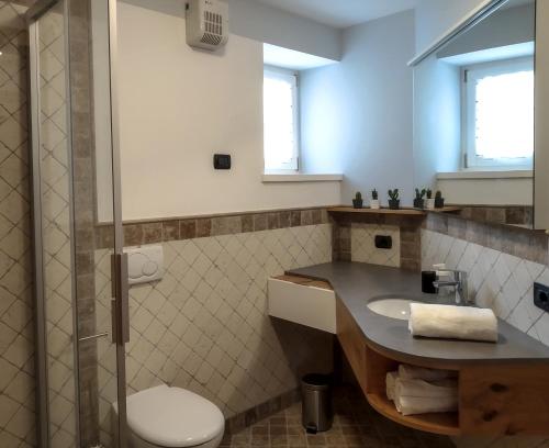 uma casa de banho com um lavatório, um WC e um chuveiro em Casa Zone em Tesero