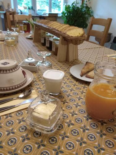 une table avec une plaque de nourriture et un pot en verre de jus d'orange dans l'établissement La Ferme Les Mamours, à La Bastide-lʼÉvêque