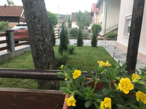 a balcony with yellow flowers and a tree at Apartments Travel in Otočac
