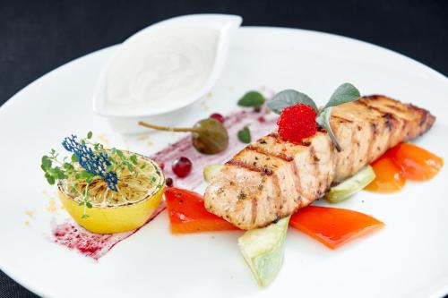a white plate of food with fish and vegetables at Carparosa Hotel in Bukovel