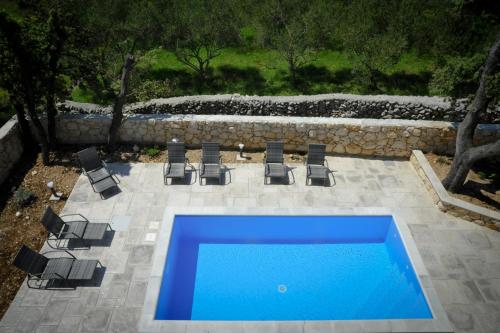 een zwembad met stoelen en een blauw zwembad bij Apartments Novak in Rab