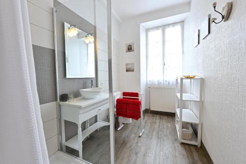 een witte badkamer met een wastafel en een spiegel bij Maison Canterou in Monein