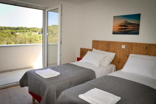 twee bedden in een kamer met een groot raam bij Apartments Novak in Rab