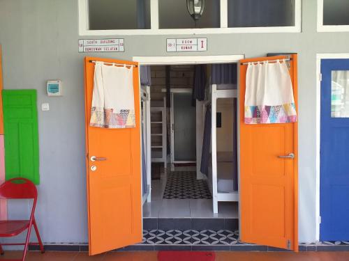 an open door to a room with orange and green doors at Home Addicts Hostel in Yogyakarta