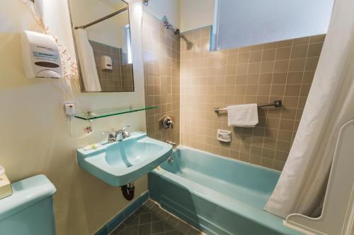 a bathroom with a sink and a bath tub at Cal Mar Hotel Suites in Los Angeles