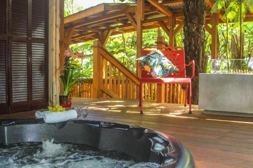 a hot tub on a deck with a red chair at At the Craters Edge in Volcano