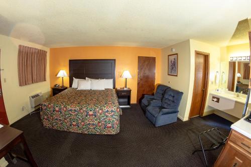 a hotel room with a bed and a blue chair at Knights Inn - Chanute in Chanute