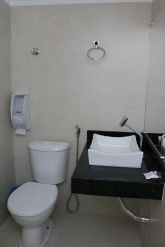 a bathroom with a white toilet and a sink at Capuchins Hotel in Porto Seguro