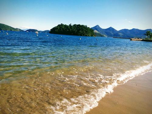 una spiaggia con una cassa d'acqua con montagne sullo sfondo di Angra TOP1 Praia Piscina Marina 2 quartos ad Angra dos Reis