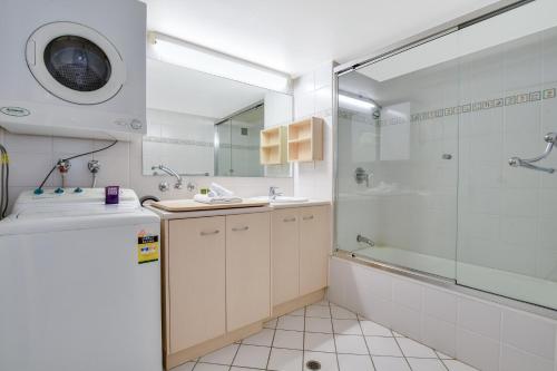 een badkamer met een douche en een wastafel bij La Mer Apartments in Mooloolaba