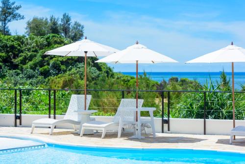 a pool with two tables and two umbrellas at Best Western Okinawa Onna Beach in Onna