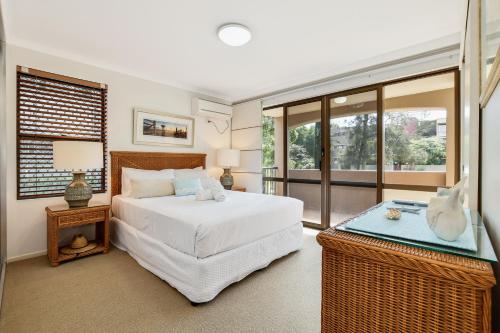 a bedroom with a white bed and a window at Beachport Apartments in Mooloolaba