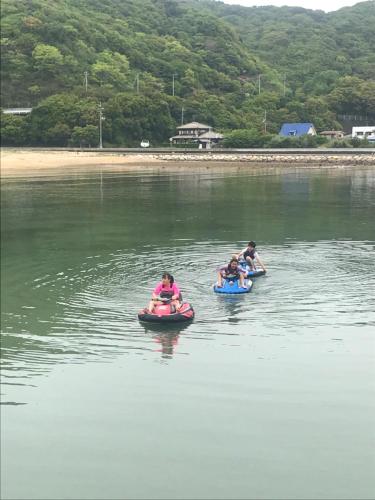 three people are riding on tubes in the water at Sea Tiger Island Inn Shodoshima in Shodoshima