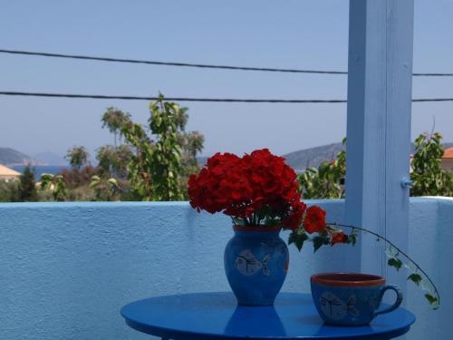 a blue vase with red flowers and a cup on a table at Ikion Studios in Steni Vala Alonissos