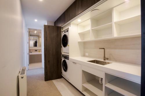 a kitchen with a sink and a washer and dryer at Peak View Residence in Queenstown