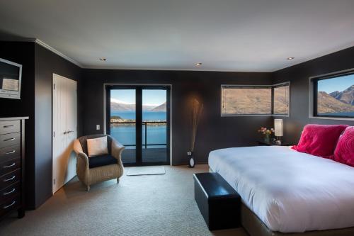 a bedroom with a large bed and a chair at Majestic View Home in Queenstown