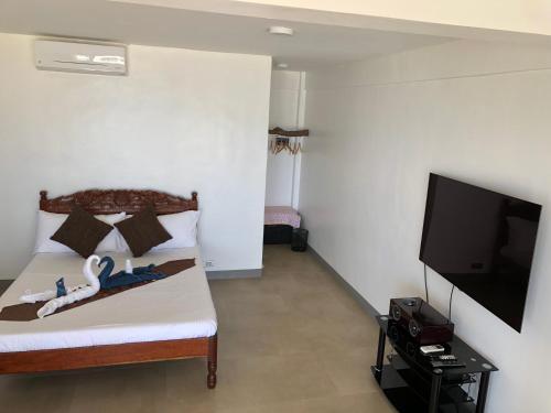 a bedroom with a bed and a flat screen tv at Sunset Cove Beach & Dive Resort in Romblon