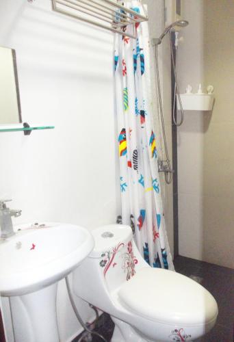 a bathroom with a sink and a toilet and a shower curtain at Abrhys Ridge Inn in Coron