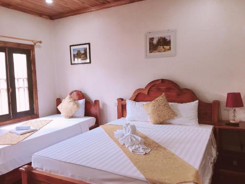two beds in a room with white walls at Elephant Boutique Hotel in Luang Prabang