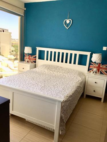 sypialnia z białym łóżkiem i niebieską ścianą w obiekcie Paradise Apartment w mieście Protaras