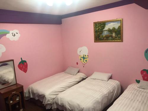 2 camas en una habitación con paredes rosas en 陽光綠堤民宿 en Taitung