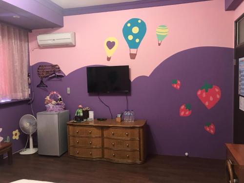 台東市的住宿－陽光綠堤民宿，一间有紫色墙壁的房间,里面装有冰淇淋和水果