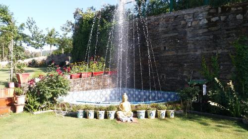 a fountain in a garden with a dog sitting under it at Rosewood Estate in Chail