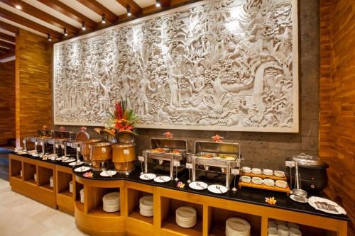 a buffet line with plates and a large painting on the wall at Astagina Resort Villa and Spa in Legian
