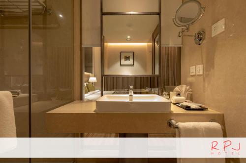 a bathroom with a sink and a mirror at RPJ Hotel Rajkot in Rajkot