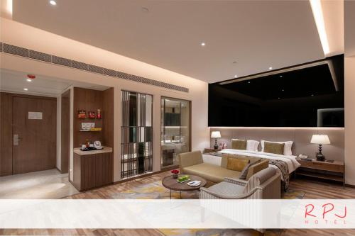 a living room with a bed and a couch and a tv at RPJ Hotel Rajkot in Rajkot