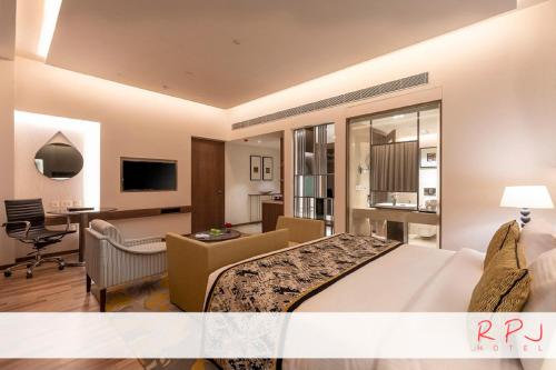 a hotel room with a large bed and a desk at RPJ Hotel Rajkot in Rajkot