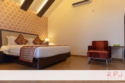 a bedroom with a bed and a chair at RPJ Hotel Rajkot in Rajkot