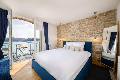 a hotel room with a large bed and a balcony at Restaurant Hotel Didier Méril in Dinard