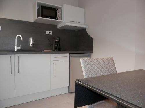 a kitchen with white cabinets and a black counter top at Appart-hôtel Chanzy / Angoulême in Angoulême