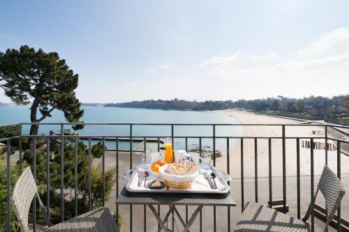 a tray of food on a table on a balcony overlooking a beach at Restaurant Hotel Didier Méril in Dinard