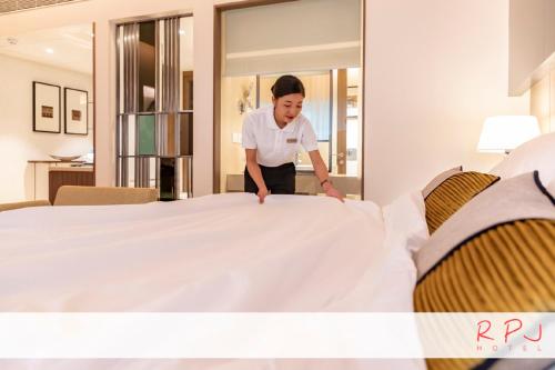 a woman is standing next to a bed at RPJ Hotel Rajkot in Rajkot