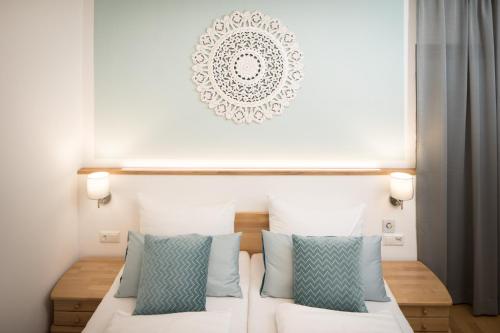 a bedroom with a white bed with blue pillows at Pension Auszeit Velden in Velden am Wörthersee