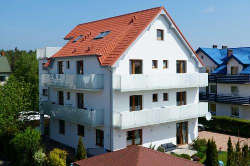 a white building with a red roof at Izba u Jędrusia in Karwia