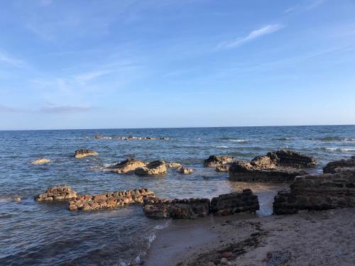 a group of rocks in the water on a beach at La Lantana Nuova in Flumini di Quartu