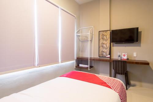 a bedroom with a bed and a tv and a window at Super OYO 360 Mangaan Residence in Medan