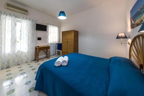 a bedroom with a blue bed with white shoes on it at Ischia Dream Sunset in Ischia