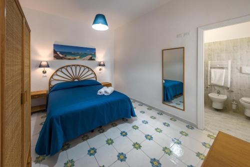 a bedroom with a blue bed and a bathroom at Ischia Dream Sunset in Ischia